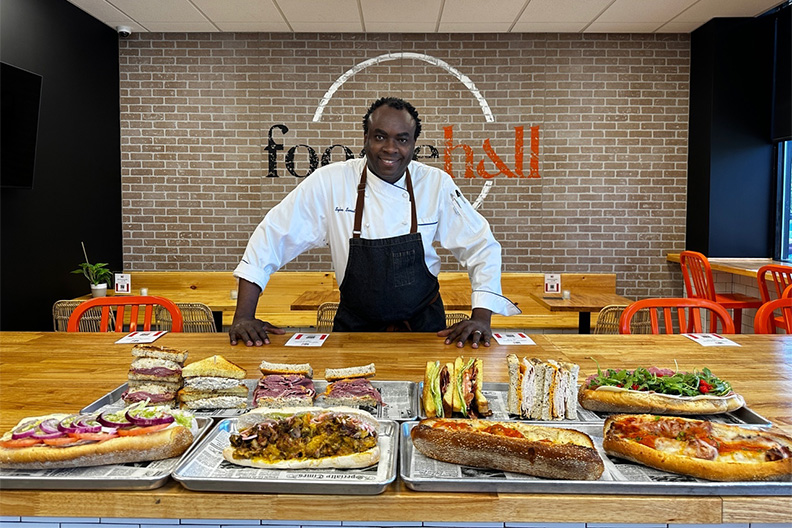 Chef Senat standing in front of a table of sandwiches at our food court near Barclay-Kingston, Cherry Hill.